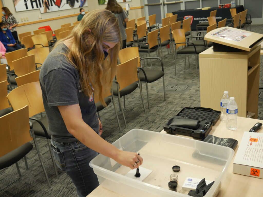 student dusting fingerprints during internship